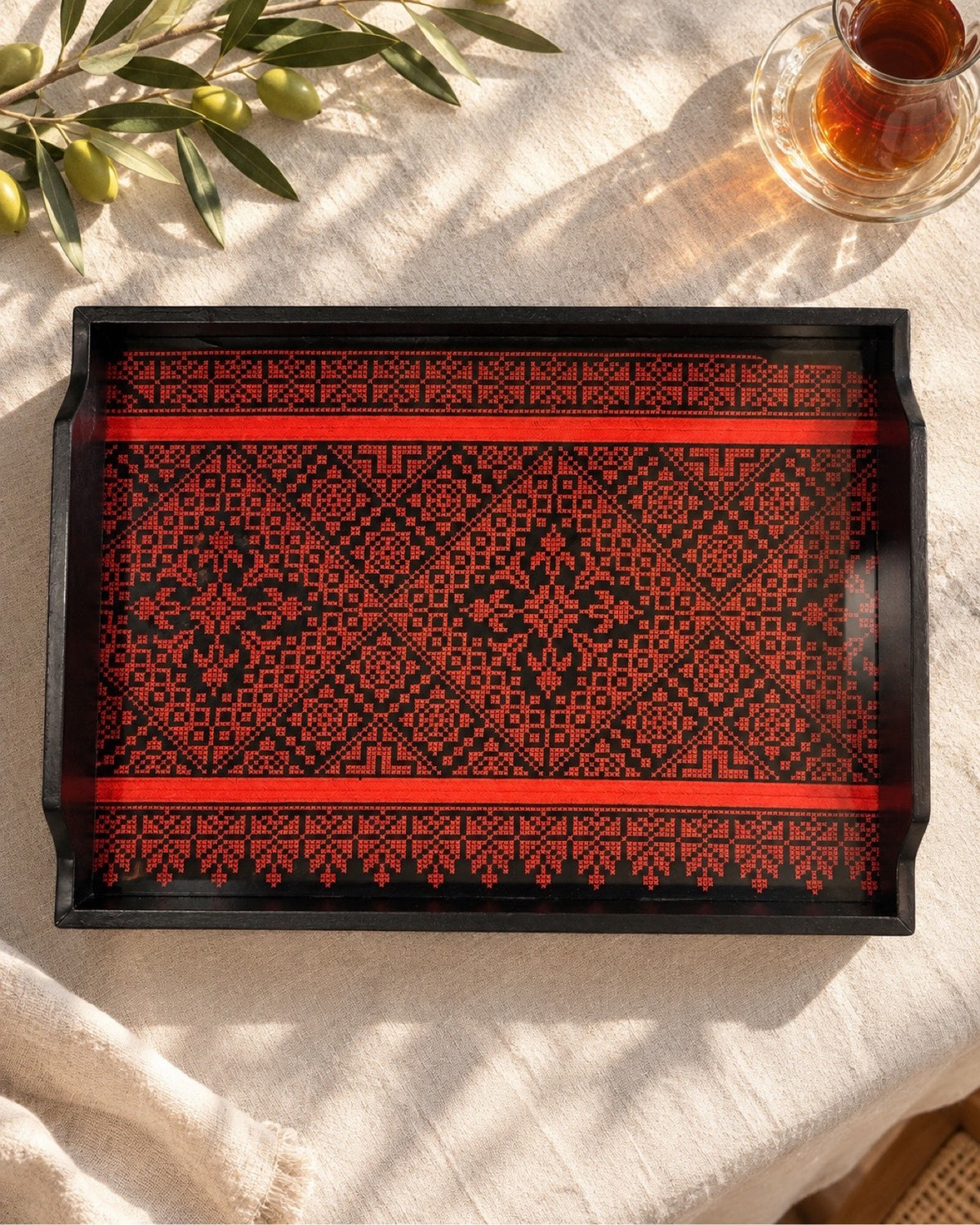 Palestinian tatreez wooden tray with a glass of tea and olives